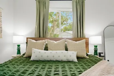 a bedroom with a green bed with pillows and a window at Game Room • Fire Pit • Arcade • Outdoor Dining in Arvada