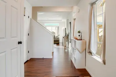 a hallway with white walls and wooden floors and a white door at Home Gym and Fenced Backyard Aurora Family Home! in Aurora