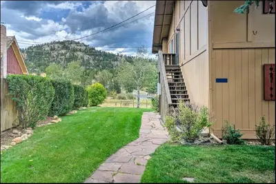 a house with a grass yard next to a building at Estes Escape-Walk Downtown - Free Mountain Coaster in Estes Park