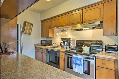 a kitchen with wooden cabinets and a stove top oven at Estes Escape-Walk Downtown - Free Mountain Coaster in Estes Park