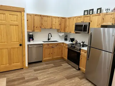a kitchen with wooden cabinets and a stainless steel refrigerator at Renovated 3BR Mountain Condo - Kids Ski Free condo in Keystone