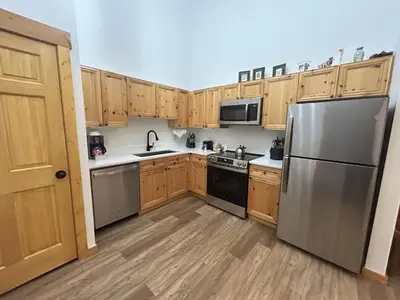 a kitchen with wooden cabinets and stainless steel appliances at Renovated 3BR Mountain Condo - Kids Ski Free condo in Keystone