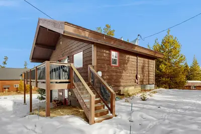 a log cabin with a staircase in the snow at The Meandering Moose in Grand Lake