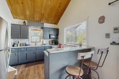 a kitchen with blue cabinets and two bar stools at The Meandering Moose in Grand Lake