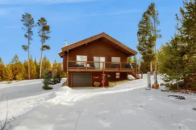a log house in the snow with a driveway at The Meandering Moose in Grand Lake