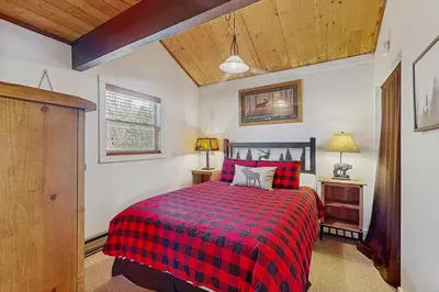 a bedroom with a bed with a red plaid blanket at The Meandering Moose in Grand Lake