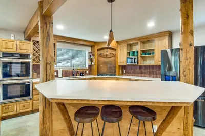 a kitchen with a large white island with two bar stools at Wooded Retreat with Private Hot Tub in Evergreen in Evergreen