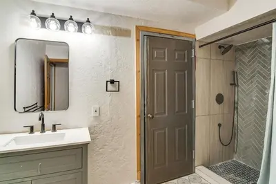 a bathroom with a sink and a shower and a mirror at Wooded Retreat with Private Hot Tub in Evergreen in Evergreen