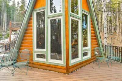a house with two chairs and windows on a deck at Wooded Retreat with Private Hot Tub in Evergreen in Evergreen