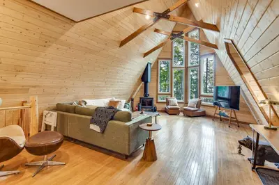 a living room with a couch and a tv at Wooded Retreat with Private Hot Tub in Evergreen in Evergreen