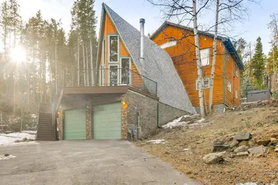 a house on a hill with a garage at Wooded Retreat with Private Hot Tub in Evergreen in Evergreen