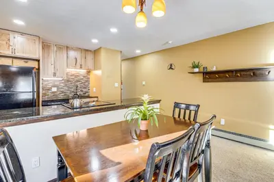 a kitchen and dining room with a wooden table and chairs at Cozy Condo Steps to Free Winter Park Shuttle! in Fraser