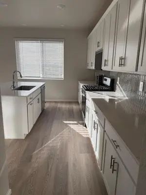 a kitchen with white cabinets and a wooden floor at Bsnsn in Commerce City