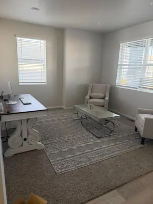 a living room with a desk and a chair and a table at Bsnsn in Commerce City