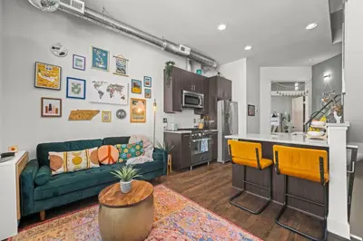 a living room with a green couch and a kitchen at Bright 1BR Office, Attached Garage & Fast WiFi in Denver