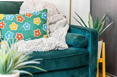 a green couch with a colorful pillow on it at Bright 1BR Office, Attached Garage & Fast WiFi in Denver