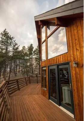a house with a wooden deck with trees in the background at The Rusty Skillet Spa and Ranch in Boulder