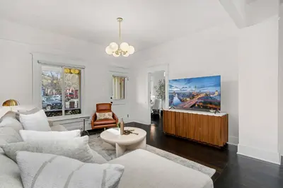a living room with white furniture and a flat screen tv at The Wild Peony Walk to Old Town FC and CSU Campus in Fort Collins