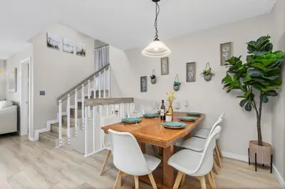 a dining room with a wooden table and white chairs at Chimney Park Retreat King Suite and Fenced Yard in Windsor
