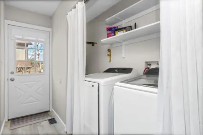 a white laundry room with a washer and dryer at Chimney Park Retreat King Suite and Fenced Yard in Windsor