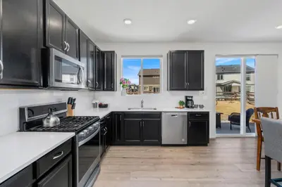 a kitchen with black cabinets and white counter tops at Pelican Landing Modern 3BD in Lakes at Centerra in Loveland