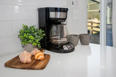 a cutting board with vegetables on a counter with a coffee maker at Pelican Landing Modern 3BD in Lakes at Centerra in Loveland