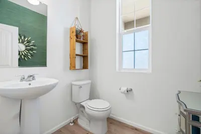 a bathroom with a toilet and a sink and a window at Pelican Landing Modern 3BD in Lakes at Centerra in Loveland