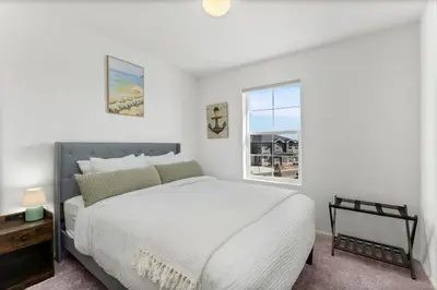 a white bedroom with a large bed and a window at Pelican Landing Modern 3BD in Lakes at Centerra in Loveland