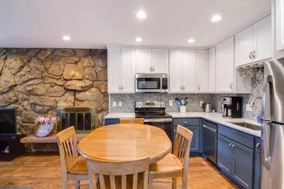 a kitchen with a wooden table and a stone wall at 3 Mi to Slopes! Family-Friendly Winter Park Escape in Winter Park