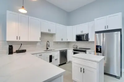 a white kitchen with white cabinets and a refrigerator at Steps to Casinos and Shuttle! Central City Home Base in Central City
