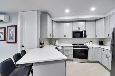 a kitchen with white cabinets and stainless steel appliances at Walkable Townhome in the Heart of Central City! in Central City
