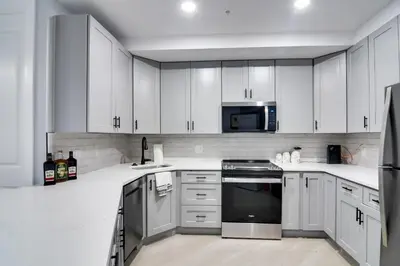 a white kitchen with stainless steel appliances and white cabinets at Walkable Townhome in the Heart of Central City! in Central City