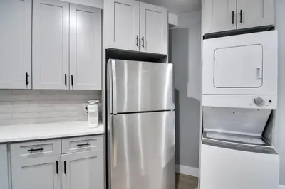 a kitchen with white cabinets and a stainless steel refrigerator at Walkable Townhome in the Heart of Central City! in Central City