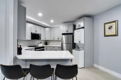 a kitchen with white cabinets and black chairs at Walkable Townhome in the Heart of Central City! in Central City