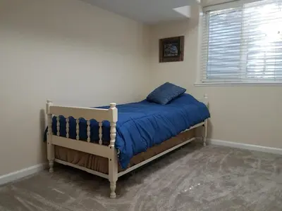 a bedroom with a bed with a blue comforter and a window at Renovated 2BR flat near Red Rocks-Rocky Mt-DT-15min in Golden