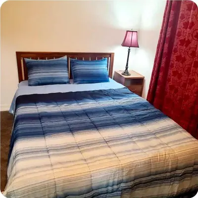 a bed with a blue and white comforter and a lamp at Comfort stay near Denver airport in DEN