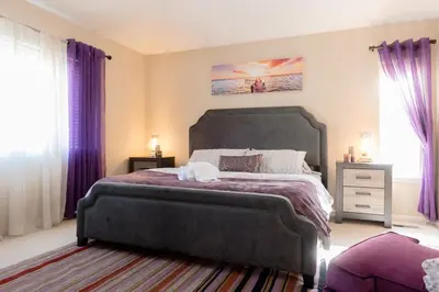 a bedroom with a large bed with purple curtains at Spacious Single Family Home in the Heart of Denver in Denver