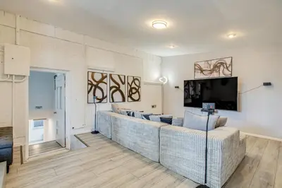a living room with a large couch and a flat screen tv at Hot Tub, Fire Pit! Group-Ready Stay Near Denver in Commerce City