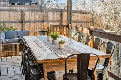 a wooden table and chairs on a deck with a fence at HotTub - Big Yard - Fireplaces - Games - Fire pit in Arvada