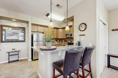 a kitchen with a counter and two bar chairs at Timbers at the Pines in Fraser