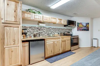 a kitchen with wooden cabinets and a brick wall at Cozy Boulder Basement Unit Upscale Outdoor Space! in Boulder