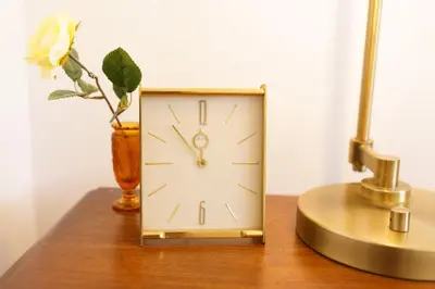a gold clock sitting on a table with a vase at Retro 70s Styled Home 15 min to Downtown in Denver