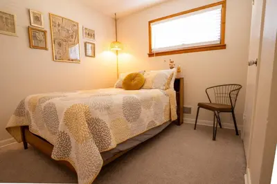 a bedroom with a bed and a chair and a window at Retro 70s Styled Home 15 min to Downtown in Denver