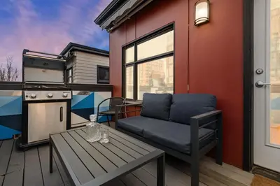 a living room with a couch and a table on a deck at Walkable Rooftop Retreat 2BR, Workspace & BBQ in Denver