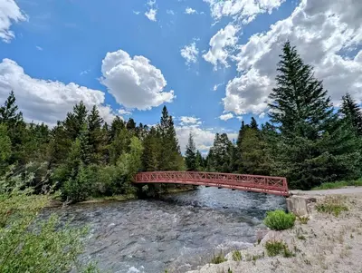a red bridge over a river in a forest at Gateway Lodge 5008 by SummitCove Lodging in Keystone