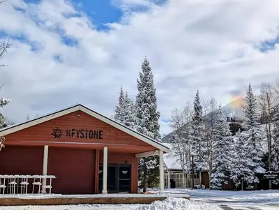 a hospice building in the snow with a rainbow in the background at Gateway Lodge 5008 by SummitCove Lodging in Keystone