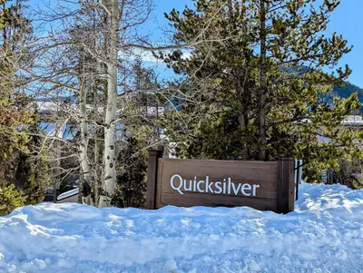 a sign in the snow next to some trees at Quicksilver 1674 by SummitCove Lodging in Keystone