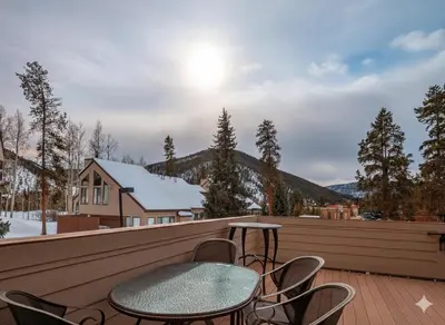a patio with a table and chairs on a deck at Quicksilver 1674 by SummitCove Lodging in Keystone