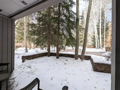 a snow covered patio with benches and trees at Chateaux DuMont 2710 by SummitCove Lodging in Keystone