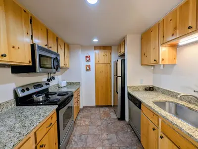 a kitchen with wooden cabinets and a stove and a sink at Decatur 1805 by SummitCove Lodging in Keystone
